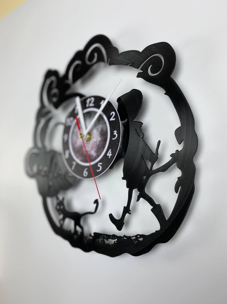 Puede incluir: Reloj de vinilo negro con una silueta de una persona paseando un gato. La esfera del reloj es blanca con n&uacute;meros y manecillas negros.