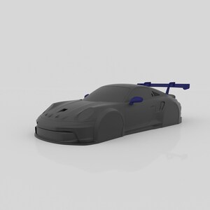 May include: A dark gray sports car model with blue side mirrors and a rear wing. The car has a sleek design with a low profile and aerodynamic features, suggesting a racing or high-performance vehicle.