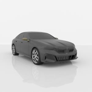 May include: A matte dark gray sedan featuring a prominent front grille, sharp angular headlights, and a sleek aerodynamic body profile. The vehicle is equipped with multi-spoke silver alloy wheels and side mirrors with a metallic gold finish.