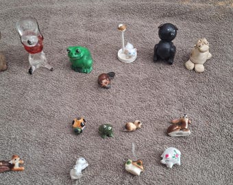 Può includere: Una collezione di piccole statuette di animali, tra cui un topo marrone, una rana verde, un cane nero e una pecora bianca. Altre statuette includono un cervo, un maiale e un cane. Le statuette sono in ceramica e vetro.