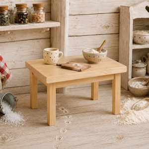 Könnte beinhalten: Ein Miniatur-Holztisch in einer rustikalen Küche mit einer kleinen gepunkteten Tasse, einem Holzschneidebrett und einer Keramikschale mit Holzlöffel. Die Umgebung umfasst verschiedene Küchenbehälter, verstreutes Mehl und kleine Pfotenabdrücke.