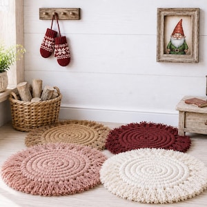 Pode incluir: Quatro bases para copos ou jogos americanos redondos e texturizados dispostos sobre uma superfície. Cada peça apresenta um design em espiral feito de corda grossa com uma borda de franjas. As cores incluem castanho claro, bordeaux, rosa velho e creme.