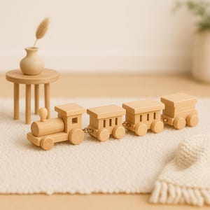 May include: A wooden toy train set with four connected carriages. The train is made of light-coloured wood and has a classic design. The set includes a locomotive and three carriages, all with wheels and simple detailing. A small wooden table and vase are in the background.