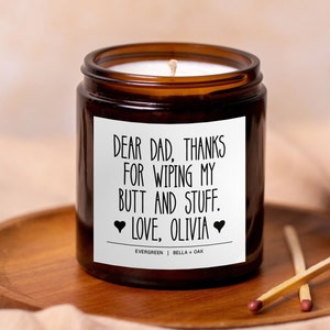May include: A brown glass candle jar with a white label that reads "DEAR DAD, THANKS FOR WIPING MY BUTT AND STUFF. ❤LOVE, OLIVIA❤ EVERGREEN | BELLA + OAK".