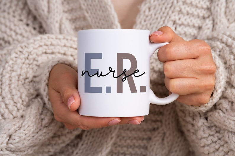 Pode incluir: Caneca de cer&acirc;mica branca com o texto "E.R. nurse" em letras pretas, cinzas e marrons.