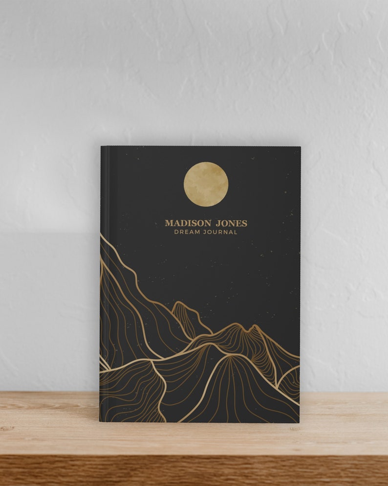 May include: Black dream journal with gold foil accents. The cover features a stylized moon and mountains with the text "MADISON JONES DREAM JOURNAL".