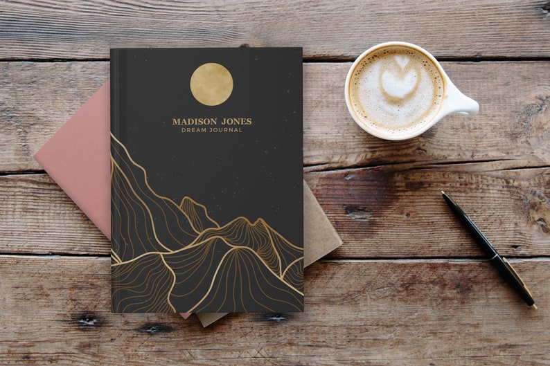 May include: A black dream journal with a gold moon and mountain design. The text "MADISON JONES DREAM JOURNAL" is printed on the cover.