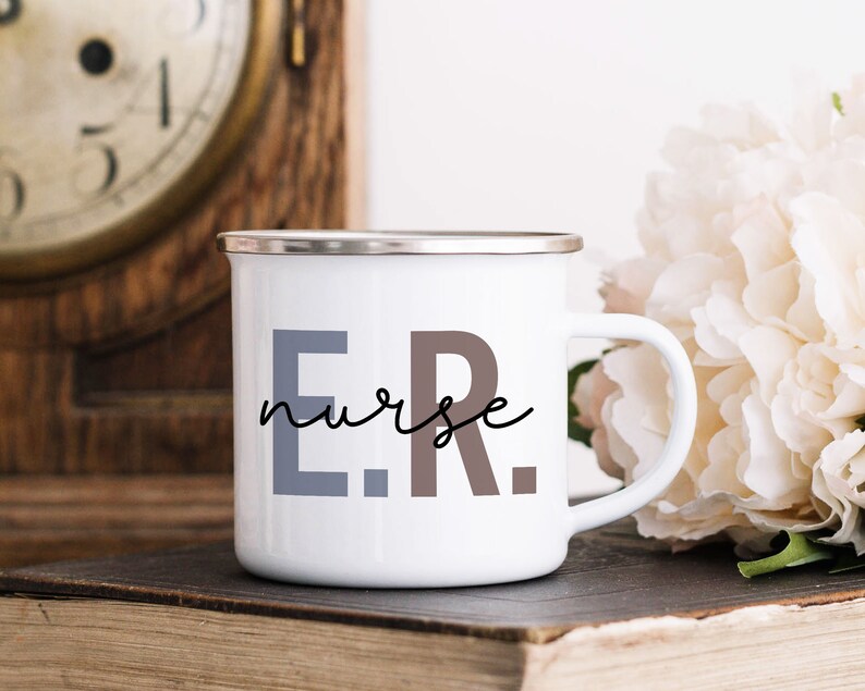 Pode incluir: Caneca de esmalte branco com borda prateada. A caneca tem o texto "E.R. nurse" impresso em preto, cinza e marrom.