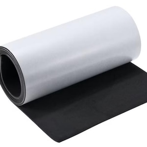 Può includere: Un rotolo di foglio magnetico nero con un retro adesivo bianco. Il foglio è arrotolato e parzialmente srotolato, mostrando sia il lato magnetico nero che il lato adesivo bianco.