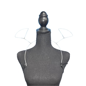 May include: A black fabric mannequin with a silver wire frame for a necklace or collar. The wire frame is shaped like a pair of wings.