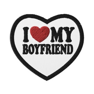 Könnte beinhalten: Weißer herzförmiger Patch mit schwarzem Umriss und rotem Herzen. Der Text "I love my boyfriend" ist in Schwarz gestickt.