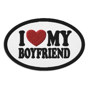 Könnte beinhalten: Weißer ovaler Patch mit schwarzem Rand und schwarzem gesticktem Text "Ich liebe meinen Freund" mit einem roten Herzen in der Mitte.