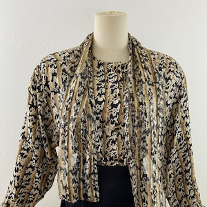 Peut inclure: Ensemble deux pi&egrave;ces vintage. Le haut pr&eacute;sente un imprim&eacute; animalier marron, noir et blanc avec des manches longues et un col drap&eacute;. La jupe est noire. L'ensemble est pr&eacute;sent&eacute; sur un mannequin.