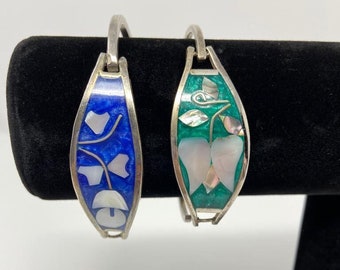May include: Two silver bracelets with enamel and mother of pearl inlay. One bracelet is blue with a floral design and the other is green with a flower design.