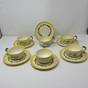May include: Set of six yellow and white teacups and saucers with a green and red floral design.