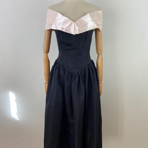 Pu&ograve; includere: Un abito nero a spalle scoperte con un corpetto in raso rosa e una gonna ampia.