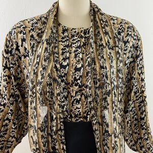 Peut inclure: Ensemble vintage deux pi&egrave;ces avec un haut &agrave; motifs et un bas noir uni. Le haut pr&eacute;sente un design boutonn&eacute; avec un motif unique dans les tons marron, noir et beige. L'ensemble est pr&eacute;sent&eacute; sur un mannequin, mettant en valeur son style.