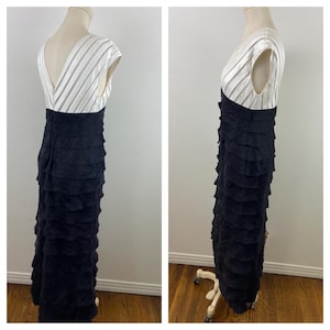 May include: A formal, floor-length dress with a white, striped bodice and a black, tiered skirt. The dress has a V-neck and cap sleeves. The skirt is made of multiple layers of fabric, creating a ruffled effect. The dress is displayed on a mannequin.
