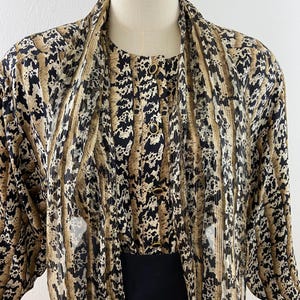 Peut inclure: Ensemble vintage compos&eacute; d'un chemisier et d'une veste &agrave; imprim&eacute; animal. Le chemisier pr&eacute;sente un devant boutonn&eacute; et un col. La veste assortie a des manches longues. L'imprim&eacute; est un m&eacute;lange de noir, de marron et de beige.