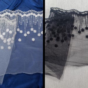 Puede incluir: Dos piezas de encaje blanco y negro con un diseño floral. El encaje tiene un borde festoneado y una franja de pequeñas flores.