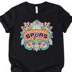 May include: A white ceramic mug with a black handle and the text "But First, Coffee" in a black, handwritten-style font. The mug is on a white surface.