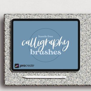 Pode incluir: Uma tela azul em um tablet mostra o texto "hassle free calligraphy brushes" em branco com um logotipo Procreate no canto inferior esquerdo. Uma caneta branca está em uma superfície cinza abaixo do tablet.