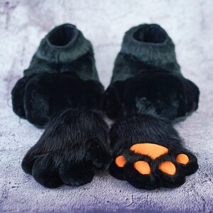 Pu&ograve; includere: Un paio di pantofole di pelliccia nera a forma di zampa con cuscinetti per zampe arancioni. Le pantofole sono realizzate in tessuto morbido e peluche e hanno una vestibilit&agrave; comoda.