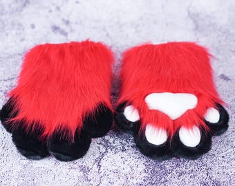 May include: A pair of red furry paw hand warmers with black paw pads and white paw pads.