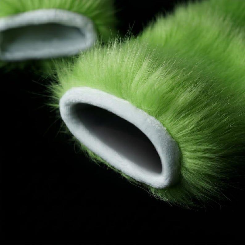 Op de afbeelding: Close-up van twee limoengroene, pluizige, imitatiebont manchetten met een witte, zachte binnenvoering. De manchetten hebben een afgeronde opening en staan tegen een zwarte achtergrond. Het bont heeft een lange, zachte textuur.