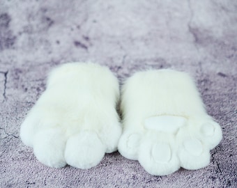 May include: A pair of white furry paw-shaped hand warmers with a white felt paw pad on each.