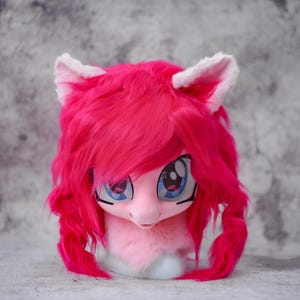 May include: A pink pony head with large blue eyes, white ears, and a pink mane and tail. The pony head is made of soft, plush material and is designed to be worn as a costume or cosplay accessory.