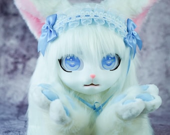 May include: A white furry plush toy with blue eyes and a blue and white lace headband. The toy is wearing a blue ribbon around its neck and has its paws in front of it.