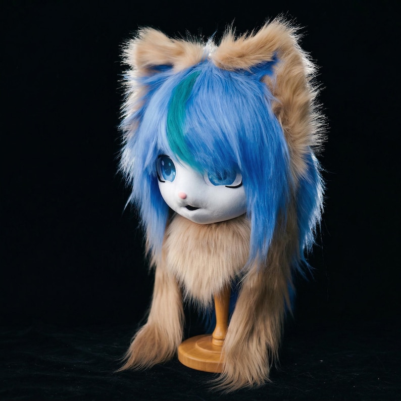 May include: An anime-style headpiece with a white face, large blue eyes, and blue and teal hair. The ears and fur are brown. The headpiece is mounted on a wooden stand against a black backdrop.