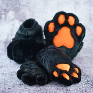 Pu&ograve; includere: Zampe pelose nere con cuscinetti arancioni. Le zampe sono per un costume di furry.