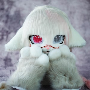 May include: A white furry plush toy with pink hair, one red eye, and one blue eye. The toy is holding its paws in front of its face.