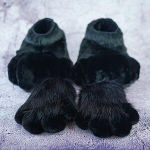 Pu&ograve; includere: Un paio di pantofole a forma di zampa di pelliccia nera con dita dettagliate. Le pantofole sono realizzate in tessuto morbido e peluche e hanno una forma di zampa realistica.
