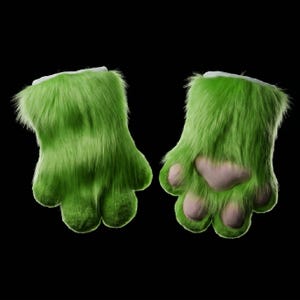 Op de afbeelding: Een paar felgroene, harige poothandschoenen met lichtroze voetzolen. De handschoenen hebben een witte manchet aan de bovenkant en staan tegen een zwarte achtergrond. De handschoenen zijn ontworpen om op dierenpoten te lijken.
