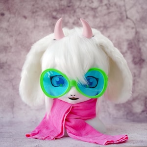 May include: A white wig with two small pink horns, featuring long, soft, floppy ears. The wig is styled with straight bangs and is accessorized with large, bright green-rimmed sunglasses with blue lenses and a long, vibrant pink fabric scarf.