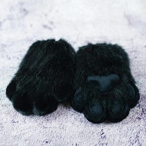 Puede incluir: Un par de guantes de pata de piel sint&eacute;tica negra. Cada guante presenta un exterior de felpa y peludo con una almohadilla de pata lisa y acolchada y detalles individuales de los dedos. Los guantes est&aacute;n dise&ntilde;ados para parecerse a patas de animales.