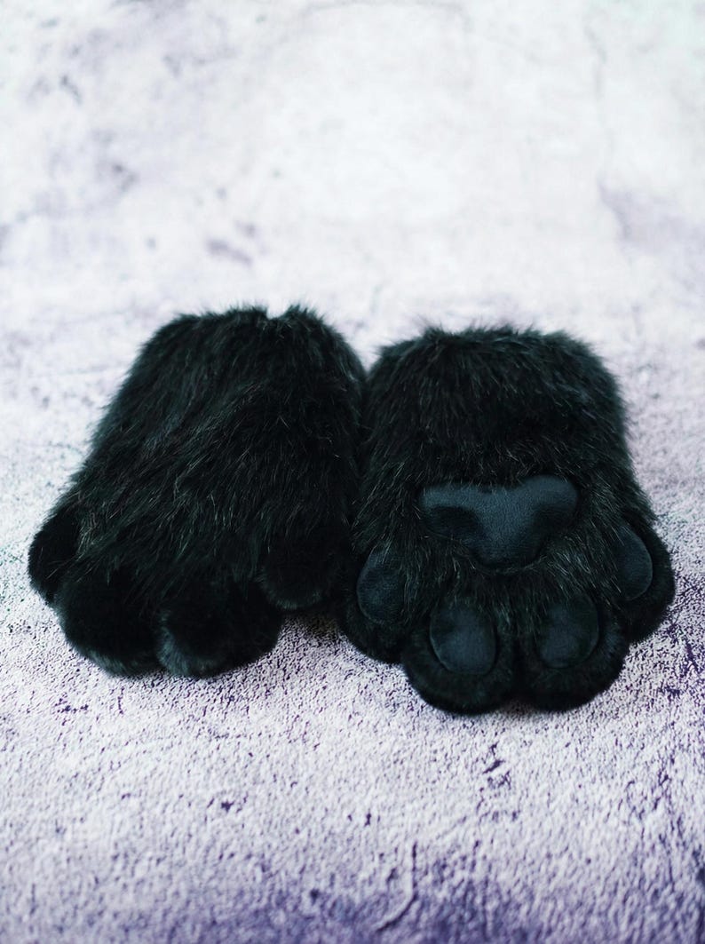 Puede incluir: Un par de guantes de pata de piel sint&eacute;tica negra. Cada guante presenta un exterior de felpa y peludo con una almohadilla de pata lisa y acolchada y detalles individuales de los dedos. Los guantes est&aacute;n dise&ntilde;ados para parecerse a patas de animales.