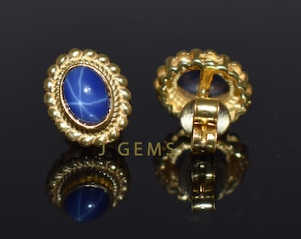 Puede incluir: Un par de pendientes de oro con piedras preciosas de zafiro estrella azul. Los pendientes tienen un diseño detallado en forma de cuerda alrededor de las piedras preciosas.