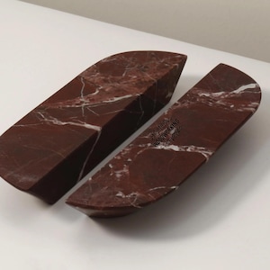 Könnte beinhalten: Zwei rotbraune Marmorstücke mit weißen Adern. Die Stücke haben eine gebogene, rechteckige Form mit flachem Boden und abgewinkelten Seiten. Der Marmor hat eine polierte Oberfläche. Der Text "WOODWORKING" ist auf einem Stück sichtbar.