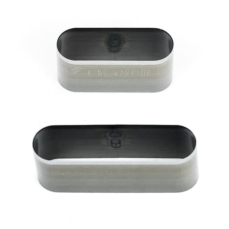 May include: Two silver metal oval-shaped punch tools. The top tool has the text "KING WARRIOR" engraved on the side. The bottom tool has the text "KING WARRIOR" engraved on the side.