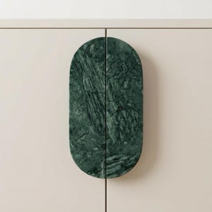 May include: A cabinet door with a dark green marble oval handle. The handle is split in two, with the marble showing natural veining. The cabinet door is a light beige colour.