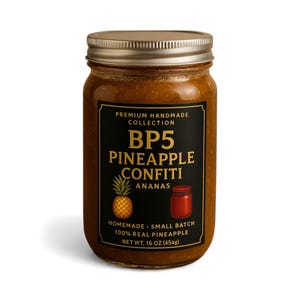 May include: A glass jar of pineapple confit with a gold lid and a black label. The label reads "BP5 PINEAPPLE CONFITI ANANAS" and "100% REAL PINEAPPLE, NET WT. 16 OZ (454g)". A pineapple and a jar illustration are also on the label.