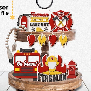 May include: A tiered wooden tray decorated with red, yellow, and black firefighter themed cutouts. The cutouts include a fire truck, a fireman, a fire hydrant, a fire axe, and a fire helmet. The text "Fireman First In Last Out" and "Be Brave!" are also included.
