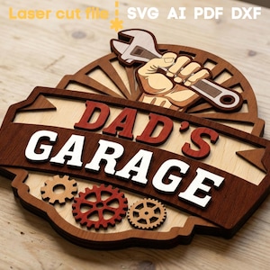 May include: Wooden sign with the text "DAD'S GARAGE" in white and red lettering. The sign features a hand holding a wrench, gears, and a decorative border. The sign is made of layered wood.