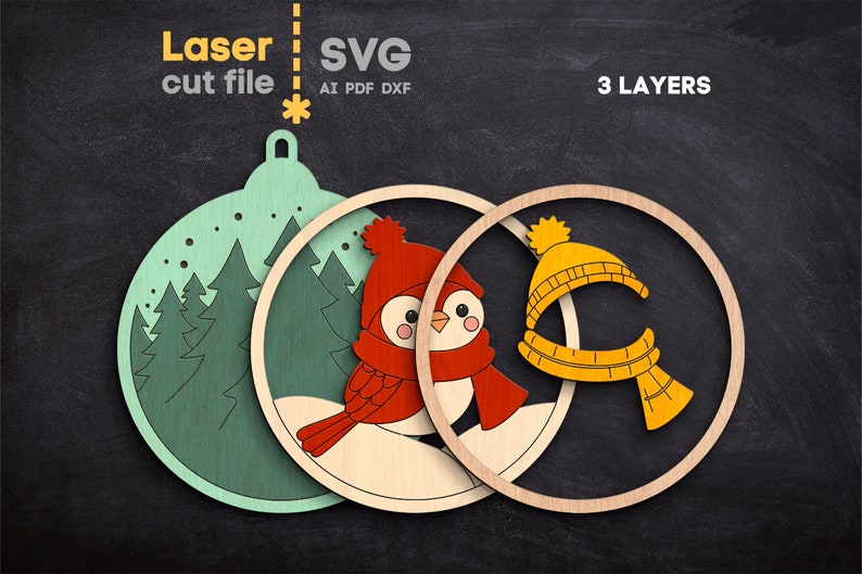 May include: A three-layer laser cut file design featuring a light green ornament shape with a forest scene, a middle layer with a red bird wearing a red hat and scarf, and a top layer with a yellow hat and scarf. Text reads Laser cut file SVG AI PDF DXF 3 LAYERS.