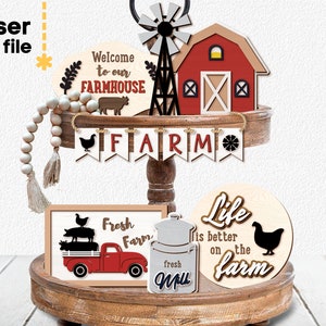 May include: A tiered wooden tray with farmhouse themed decorations. The top tier has a red barn, a windmill, and a sign that says "Welcome to our FARMHOUSE". The middle tier has a banner that says "FARM" and a string of wooden beads. The bottom tier has a sign that says "Fresh Farm", a red truck with pigs on the back, a milk jug, and a round sign that says "Life is better on the farm".