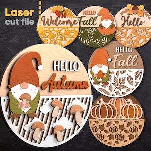 Puede incluir: Cinco adornos de madera cortados con láser que representan gnomos y diseños de otoño. Los adornos presentan el texto "Hello Fall", "Welcome Fall", "Hello Autumn" y "Hello".